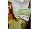 Vintage bathroom featuring a green tiled wall, classic fixtures and retro pattern flooring at 229 Maple Dr, Oxford, NC 27565