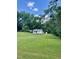Charming white home with a lush green lawn and a metal carport, surrounded by mature trees at 229 Maple Dr, Oxford, NC 27565