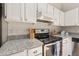 Close up of modern kitchen featuring white cabinets, granite countertops and stainless steel stove at 2849 Rue Sans Famille, Raleigh, NC 27607