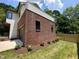 View of a red brick exterior with a garage and newly planted landscaping with grass, and a wooden fence in the background at 333 Merrywood Dr, Raleigh, NC 27610