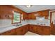 A kitchen with wooden cabinets, a cooktop, and a window overlooking the outdoors at 3701 Oak Grove Church Rd, Mebane, NC 27302