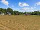 View of multiple outbuildings on vast acreage with blue skies and scattered clouds at 4050 Culbreth Rd, Stem, NC 27581