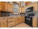 Well-equipped kitchen with natural wood cabinetry and modern black appliances at 4050 Culbreth Rd, Stem, NC 27581