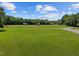 A large open field with outbuildings surrounded by a dense forest with green grass and a dirt road at 4050 Culbreth Rd, Stem, NC 27581