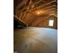 Unfinished attic space featuring exposed wooden beams and a small window, offering potential for customization at 421 Braxman Ln, Holly Springs, NC 27540