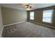 Bright, carpeted bedroom featuring two windows and a ceiling fan at 421 Braxman Ln, Holly Springs, NC 27540