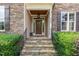Stone entryway with a decorative wood door and black metal handrails and lush greenery at 4228 Fawn Lily Dr, Wake Forest, NC 27587