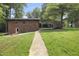 Brick home featuring a lush green lawn, walkway, mature trees and a convenient carport at 437 Woodsdale Rd, Roxboro, NC 27573