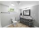 Bathroom with a toilet, double sink vanity, dark mirror, and modern lighting fixture at 437 Woodsdale Rd, Roxboro, NC 27573