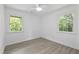 Bright bedroom with hardwood floors, ceiling fan, and two windows with views of the outdoors at 437 Woodsdale Rd, Roxboro, NC 27573