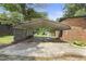 View of the carport showing a brick home, lush yard, storage shed and outbuilding in the background at 437 Woodsdale Rd, Roxboro, NC 27573