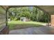 View from inside the carport showcasing the storage shed and lush greenery in the background at 437 Woodsdale Rd, Roxboro, NC 27573