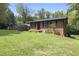 A quaint brick home with black shutters surrounded by a lush, green lawn and a storage shed at 437 Woodsdale Rd, Roxboro, NC 27573