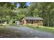 Charming brick home featuring a lush lawn, carport, and an outbuilding, nestled among mature trees at 437 Woodsdale Rd, Roxboro, NC 27573