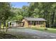 Charming brick home featuring a lush lawn, carport, and an outbuilding, nestled among mature trees at 437 Woodsdale Rd, Roxboro, NC 27573