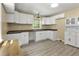 Well-lit kitchen with white cabinets, gray vinyl floors, and a ceiling fan at 437 Woodsdale Rd, Roxboro, NC 27573