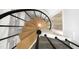 Birds-eye view of a spiral staircase featuring hardwood steps, a black metal railing, and white trim at 437 Woodsdale Rd, Roxboro, NC 27573
