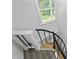 A spiral staircase features hardwood steps, a black metal railing and trim, and a bright window at 437 Woodsdale Rd, Roxboro, NC 27573