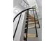 Low angle view of spiral staircase, featuring a black metal railing, hardwood steps, and white trim at 437 Woodsdale Rd, Roxboro, NC 27573