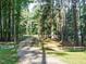 Gated gravel driveway lined by mature trees at the entrance of the property at 45 Softwood Dr, Franklinton, NC 27525