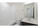 Well-lit bathroom featuring a tub with tile surround, a modern vanity, and a framed mirror at 485 Hawksbill Dr, Franklinton, NC 27525