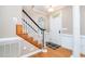 Inviting foyer with hardwood floors, staircase with dark railing, and a bright front door at 5113 Linksland Dr, Holly Springs, NC 27540