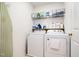 Functional laundry room features washer, dryer, ironing board and cleaning supplies on wall-mounted shelving at 5113 Linksland Dr, Holly Springs, NC 27540