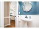 Traditional powder room with pedestal sink, round mirror and wood paneling at 5113 Linksland Dr, Holly Springs, NC 27540