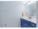 Stylish powder room featuring a modern blue vanity with a round mirror and sleek fixtures at 512 Mill Hopper Ln, Apex, NC 27502