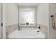 Bathroom featuring a relaxing soaking tub with tile accents and a bright, frosted window at 512 Mill Hopper Ln, Apex, NC 27502