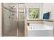 Bathroom featuring a glass-enclosed shower, a soaking tub, and a bright window at 529 Lake Gaston Dr, Fuquay Varina, NC 27526