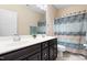 Bathroom featuring a double vanity with dark cabinets, a shower/tub with curtain, and neutral tile flooring at 529 Lake Gaston Dr, Fuquay Varina, NC 27526
