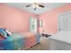A bedroom featuring light pink walls, a colorful comforter, and a bright window at 529 Lake Gaston Dr, Fuquay Varina, NC 27526