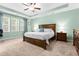 Spacious bedroom with tray ceilings, a large bed, two nightstands, and multiple bright windows at 529 Lake Gaston Dr, Fuquay Varina, NC 27526