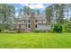 Lush backyard with mature trees, a stone chimney, and a deck perfect for outdoor gatherings at 53 Lake Wendell Rd, Wendell, NC 27591