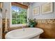 Bright bathroom featuring a soaking tub with a view of the lush green outdoors at 53 Lake Wendell Rd, Wendell, NC 27591