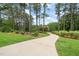 Long driveway leading to a beautiful house surrounded by lush landscaping and mature trees at 53 Lake Wendell Rd, Wendell, NC 27591