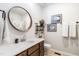 Well-lit bathroom with a round mirror, tile floors, quartz countertops and dark cabinets at 6147 Beale Loop, Raleigh, NC 27616
