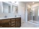 Bathroom with a double sink vanity, a large mirror, and glass enclosed shower with tiled surround at 6147 Beale Loop, Raleigh, NC 27616
