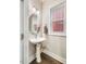 Classic powder room with pedestal sink, decorative mirror, and window with natural light at 644 Granite Mill Blvd, Chapel Hill, NC 27516