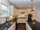 Modern kitchen featuring white cabinetry, sleek black countertops, stainless steel appliances, and stylish lighting at 723 Lindley Dr, Durham, NC 27703