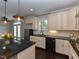 Modern kitchen with white cabinets, black countertops, stainless steel appliances, and an island with pendant lighting at 723 Lindley Dr, Durham, NC 27703