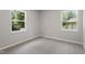 Carpeted bedroom with neutral paint and trim, featuring two windows with treed exterior views at 768 Lunar Dr, Raleigh, NC 27610