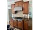 The kitchen has a cooktop with stainless steel hood, brown cabinets, tile backsplash, and granite countertops at 8228 Clarks Branch Dr, Raleigh, NC 27613