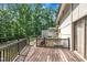 Backyard wooden deck with black railing featuring mature trees and partial view of the house exterior at 8510 Dunlee Falls Rd, Raleigh, NC 27613