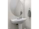 Elegant powder room with pedestal sink and decorative round mirror at 109 Grey Elm Trl, Durham, NC 27713