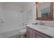 Bathroom showcasing a vanity with a light wood framed mirror, and a bathtub with white tile surround at 111 Lattimore Ln, Durham, NC 27713