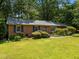 Traditional brick home featuring blue shutters, a gray roof, and lush landscaping at 111 Lattimore Ln, Durham, NC 27713