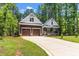 View of the home's exterior with a long driveway, two-car garage, and inviting front porch framed by lush trees at 121 Quarterhorse Dr, Louisburg, NC 27549