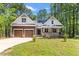 Charming home featuring a covered front porch, two-car garage, and a well-manicured lawn surrounded by lush trees at 121 Quarterhorse Dr, Louisburg, NC 27549